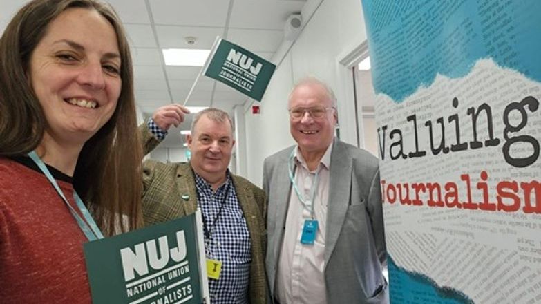 Natasha Hirst, David Nicholson & Nick Powell holding NUJ flags by a Valuing Journalism banner