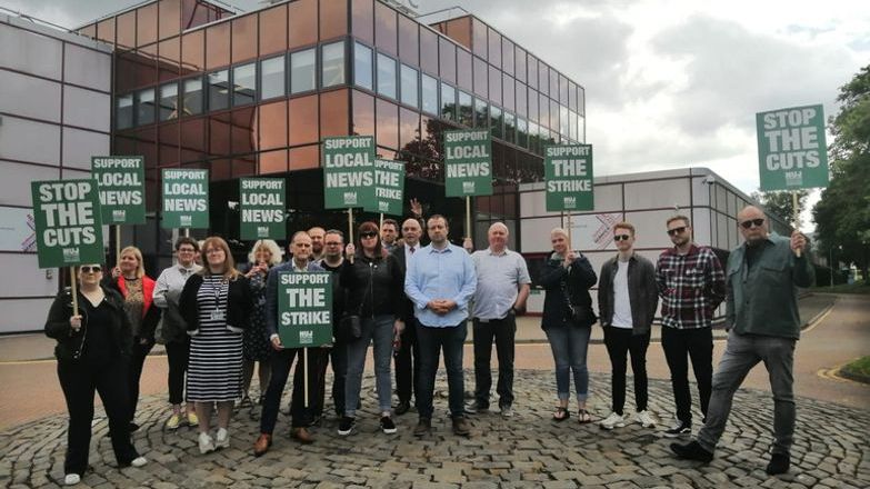 Journalists on picket hold green placards with white text 'Stop the cuts'