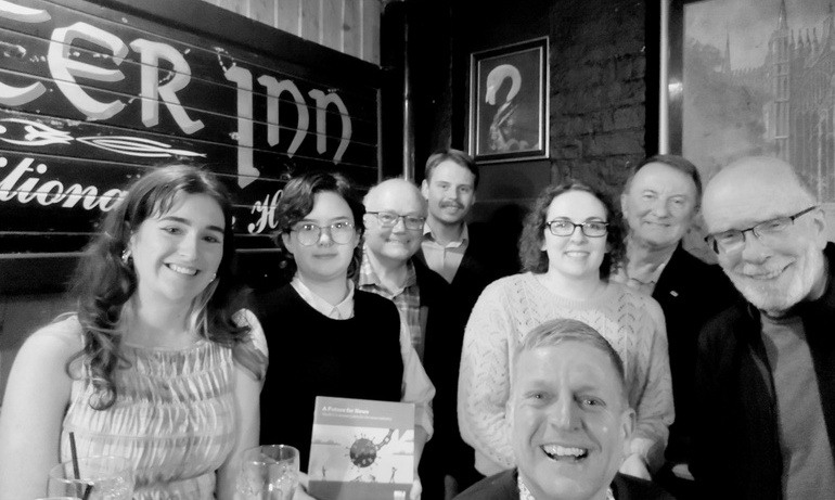 Black and white image of members smiling, one holds NUJ news recovery plan leaflet. 