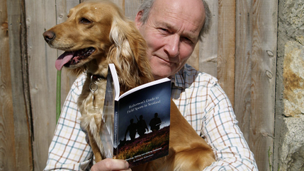 Informal shot of Alasatair Robertson with his dog and book Robertson's Guide to Field Sports in Scotland.